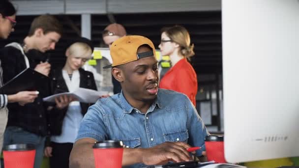Концентрований афро американський чоловік в повсякденний одяг працює на комп'ютері, отримуючи несподіваний лист при пити каву або чай серйозні людина-фрілансер мислення на робочому місці офісу — стокове відео