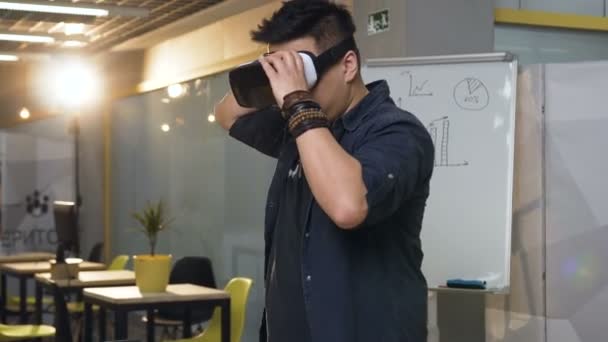 Hombre de negocios japonés que usa gafas VR de realidad virtual para trabajar en una oficina moderna y luminosa . — Vídeos de Stock