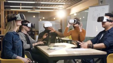 Modern ofiste vr sanal gerçeklik gözlüklerini kullanarak toplantı alan bir grup genç iş adamı.