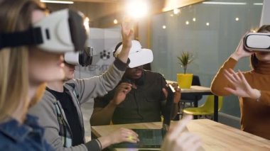 Modern ofiste vr sanal gerçeklik gözlüklerini kullanarak toplantı alan bir grup genç iş adamı.