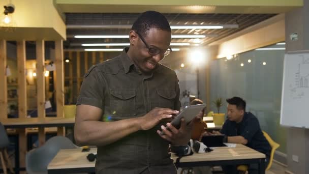 Hombre hipster joven enfocado en gafas usando tableta en la oficina . — Vídeos de Stock