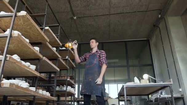 Male potter looking to the handmade vases during work day in the pottery. — Stock Video