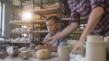 Erkek beyaz çömlekçi oğlunun vazo üzerinde desen yapma yardım.