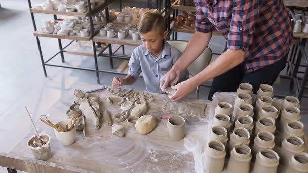 Kaukaski opiekuńczy ojciec pomaga małym synem podejmowania ceramiczny wazon. — Wideo stockowe