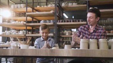 Orta yaş adam ve liitle sevimli çocuk tencere için kil yoğurma.