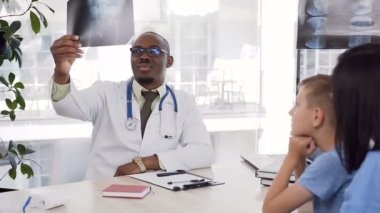 Klinikte küçük hastanın röntgenini alan Afrikalı erkek doktor.