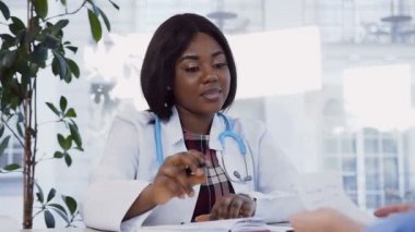 Modern klinikte kadın hastaya reçete açıklayan çekici Afrikalı doktor.