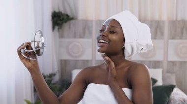 Aynada izlerken kafasına beyaz havlu ile güzel genç Afrikalı kadın portresi yüzüne kil maskesi uygulanan