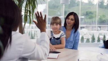 Annesinin dizlerinin üzerine oturan küçük kız kadın afican doktor beş veren.
