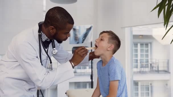 Αρσενικό γιατρό παιδίατρος, Ωτορινολαρυγγολόγος, επιθεώρηση χαριτωμένο μικρό λαιμό αγόρι. — Αρχείο Βίντεο