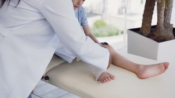 Vrouwelijke arts handen het verbinden been van schattige jongen. — Stockvideo