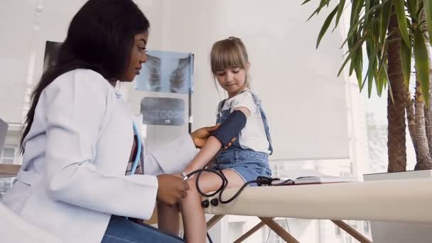 El joven médico africano mide la presión en la clínica . — Vídeos de Stock