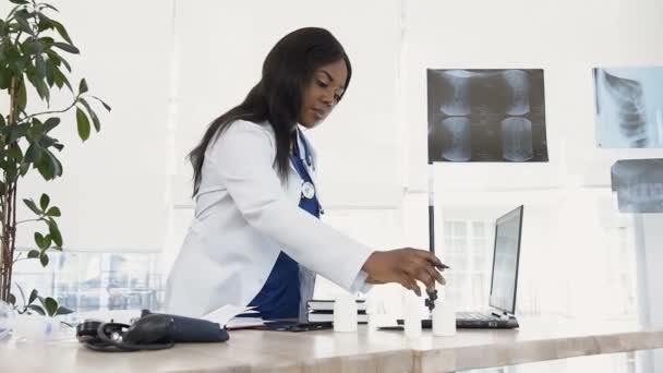 Jeune femme médecin avec stéthoscope sur la pilule de contrôle du cou et notant dans l'ordinateur portable . — Video