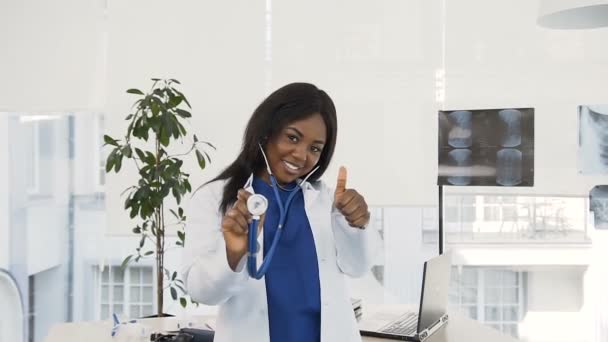 Retrato de médico feminino confiante em casaco branco e com estetoscópio na mão sorrindo para a câmera no hospital . — Vídeo de Stock