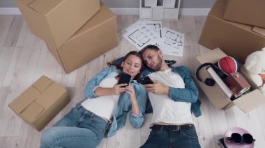 Mutlu çift yere yatarken ve akıllı telefon kullanarak.