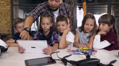 Bilgisayar sınıfında bilgisayar programlama eğitimi tablet pc kullanan Koreli adam ile beş kafkas çocuk grubu