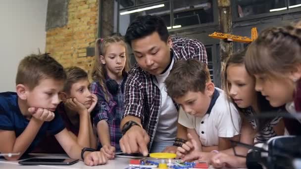 教師と創造的な子供たちは、ファンと電子コンストラクターを起動し、懐中電灯を回します.学校で彼の技術プロジェクトに取り組んでいる教師と創造的な生徒 — ストック動画