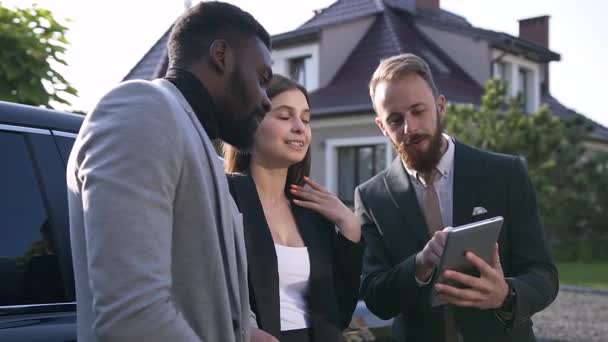 Knappe bebaarde autodealer met behulp van Tablet, het tonen van klanten functies van gekochte auto — Stockvideo