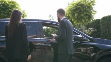 Lüks arabaya yaklaşan muhteşem genç çift, adam kadın için bir kapı açıyor ve o ön koltukta oturuyor