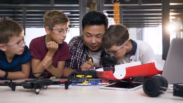 Docent elektrotechnicus samen met blanke studenten die werken met model van auto robot — Stockvideo