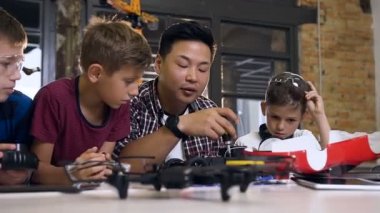 Modern okul laboratuvarında çalışan ve model elektrikli araba test beyaz okul çocukları ile Asyalı elektronik mühendisi. Bilim ve teknoloji