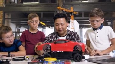 Modern okulda masada robot makine sökmek için tornavida kullanarak küçük çocuklar ile elektronik mühendisi genç Koreli adam