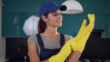 Mavi-siyah mutfak temizlemek için koruyucu eldiven giyen temizlik hizmeti güzel gülümseyen kadın