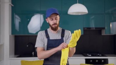 Mutfak temizliği için iş kıyafeti genç sakallı adam sarı eldiven giyer