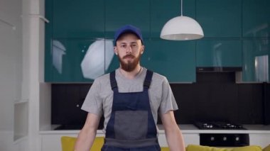 Çağdaş mutfağında katlanmış kolları ile ayakta iş elbisesi giymiş temizlik hizmeti çekici sakallı adam