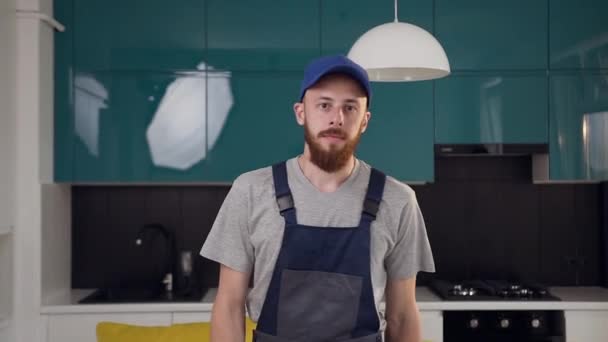 Attraente giovane uomo barbuto dal servizio di pulizia in piedi nella cucina contemporanea — Video Stock