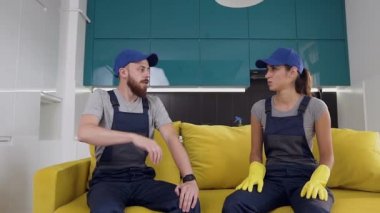 Mutfağı temizledikten sonra açık yeşil kanepede oturan temizlik hizmeti yorgun işçiler
