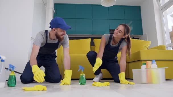 Хорошо выглядящие счастливые молодые люди из компании по уборке дают пять во время мытья пола в кухне — стоковое видео