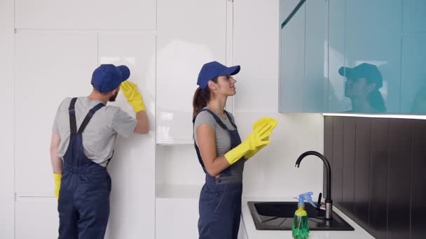 Jovens trabalhadores bonitos da empresa de limpeza em luvas de borracha limpando a cozinha oi-tech — Vídeo de Stock