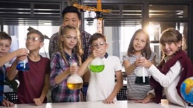 Koreli bilim adamının kimyasal deney yapan genç öğrencilere ders verdiği portre fotoğrafı, yoğun buharlaşmaya, dumana neden olan liguid ile şişe tutan çocuklar