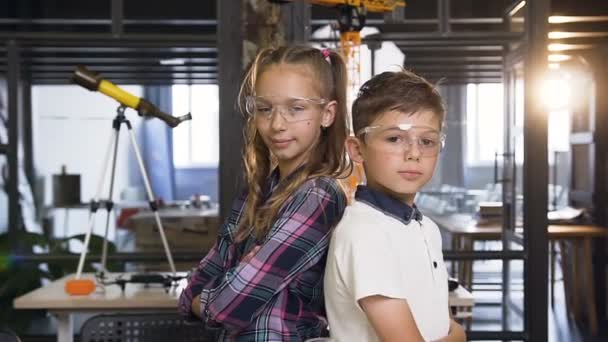 小学校の化学クラスで親指を示す安全ゴーグルで2人の陽気な白人科学者の子供の肖像写真 — ストック動画