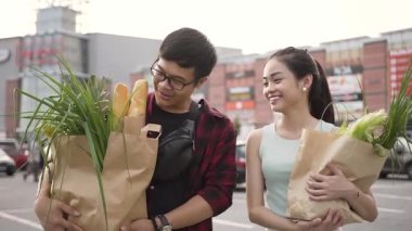 Çeşitli gıda dolu çanta ile süpermarketten gidiyor yakışıklı gülümseyen vietnamlı çift