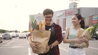 Süpermarket yakınında ürünleri ile ellerinde büyük gıda torbaları taşıyan sevimli mutlu Vietnamlı çift