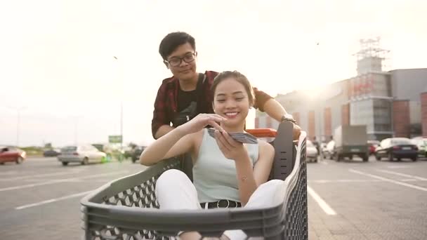 Jovens vietnamitas alegres se divertindo no fundo do grande centro comercial — Vídeo de Stock
