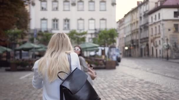 Hübsche junge Frau fotografiert ihre lächelnden fröhlichen gemischten Rassenfreunde vor dem Hintergrund des gemütlichen Straßencafés — Stockvideo