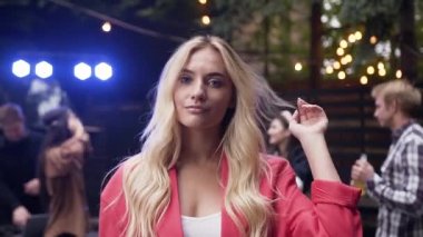 İnsanların dans grubu yakınında sevimli gülümseme ile kamera poz muhteşem sarışın kadın yakın