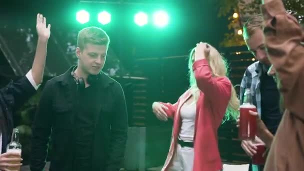 Jovens simpáticos e alegres dançando com a música inflamatória tocada pelo DJ durante seu encontro amigável — Vídeo de Stock