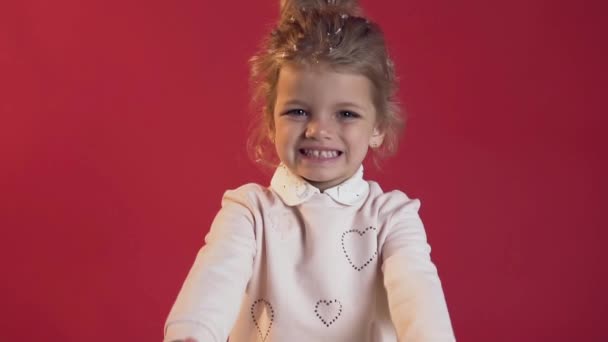 Primer plano de la increíble niña feliz en blusa blanca con hermoso regalo envuelto posando en la cámara sobre el fondo rojo — Vídeos de Stock