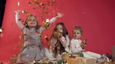 Üç güzel neşeli model çocuklar kusma ve stüdyo odasında altın konfeti yağmur yapma