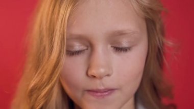 Kırmızı saçlı ve mavi gözlü ciddi güzel genç kız kırmızı arka planda kamera poz