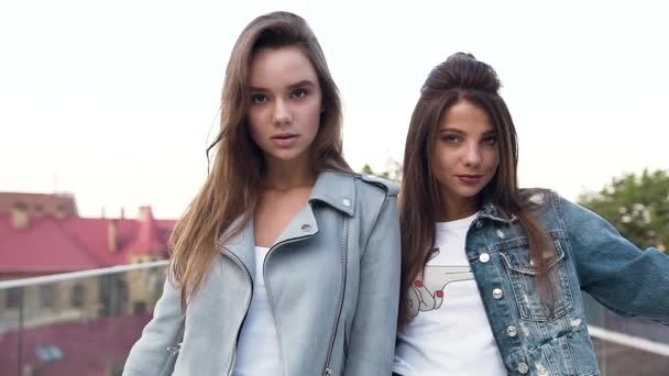 Primer plano de dos atractivas novias sexy de pie cerca de la bicicleta en la terraza de la azotea y mirando a la cámara — Vídeos de Stock