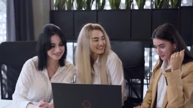 Memnun iş kadınları toplantı masasındaki bilgisayardaki ortak projelerini başarıyla tamamladıktan sonra beşlik çakıyor.