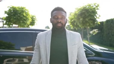 Resmi takım elbiseli başarılı Afro-Amerikan iş adamının portresi. Araba galerisinin yanındaki otoparkta yeni araba anahtarları var..
