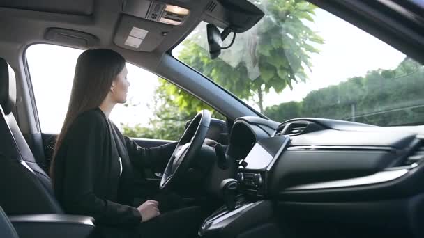 Giovane donna d'affari caucasica di successo seduta in auto nuova sul parcheggio accanto alla concessionaria. La ragazza mostra emozioni felicità seduta al volante nella sua nuova auto. Dolly ha sparato. — Video Stock