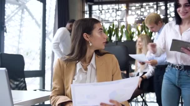 Aantrekkelijke jonge twee zakenvrouwen werken samen met financiële rapporten en tablet pc in modern kantoor — Stockvideo