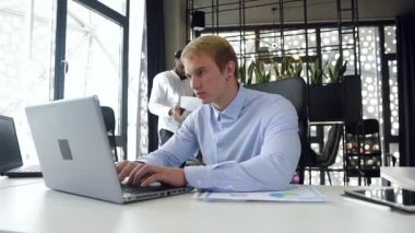 Modern ofisin işyerindeki bilgisayarında iş arkadaşlarıyla yazı yazan 30 yaşında tecrübeli bir ofis çalışanı.
